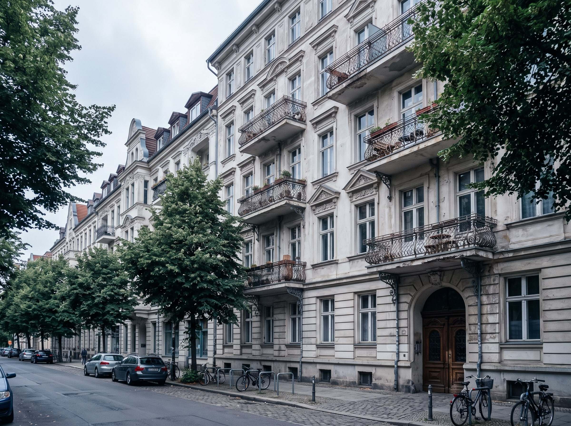Gründerzeit-Mehrfamilienhaus mit Balkonen in einer baumbestandenen Straße